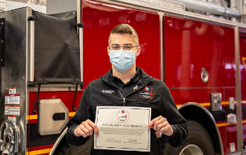 paramedic student wearing mask holding certificate posing for picture