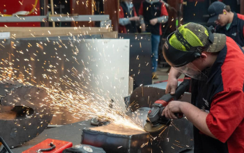 student working on metal letter with sparks flying