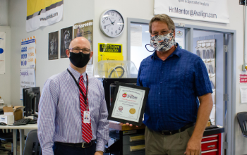 superintendent presenting certificate to teacher and posing for picture in masks