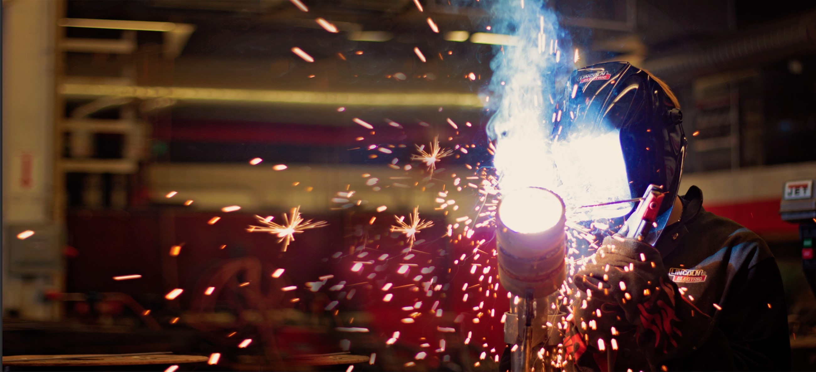 person welding with welding helmet on and sparks flying