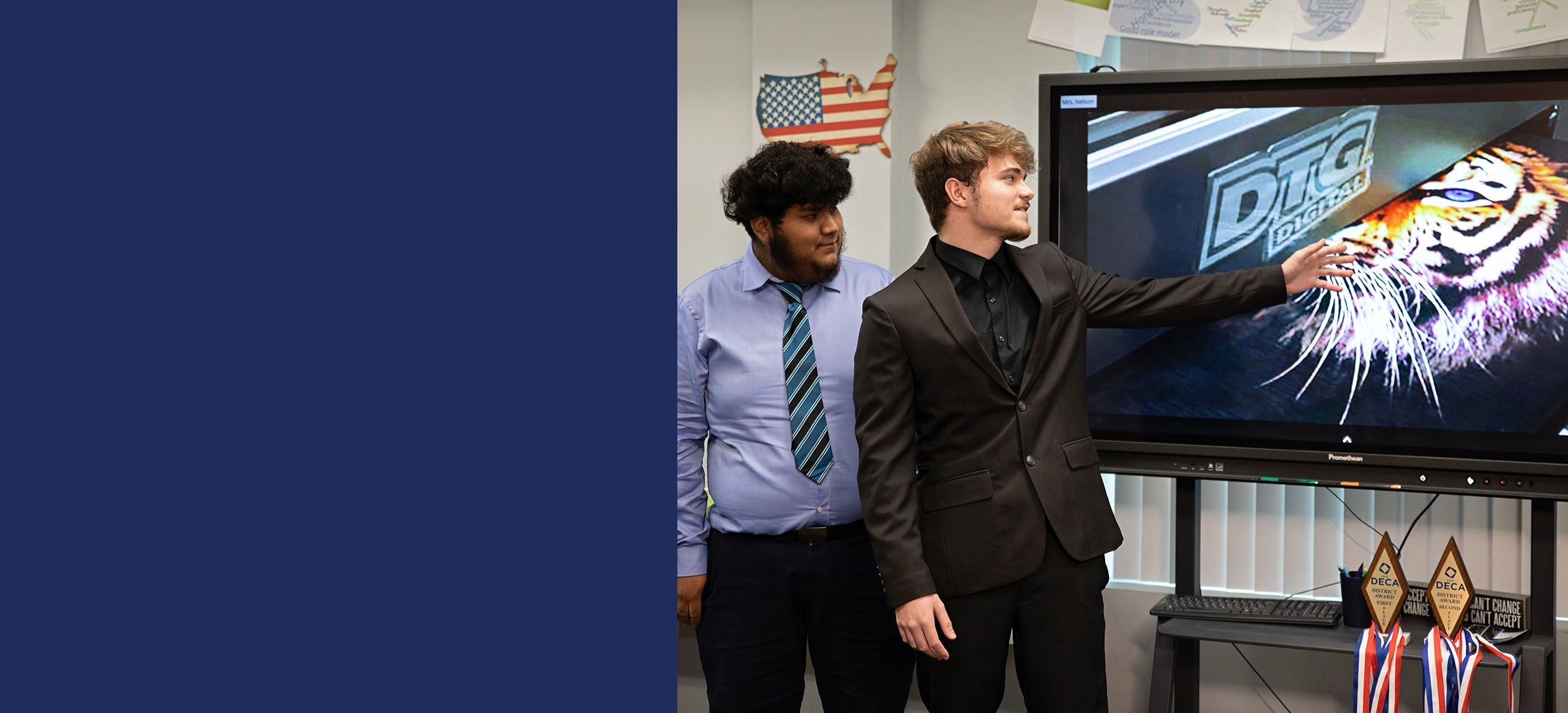 Two marketing students pointing to a display monitor giving a presentation